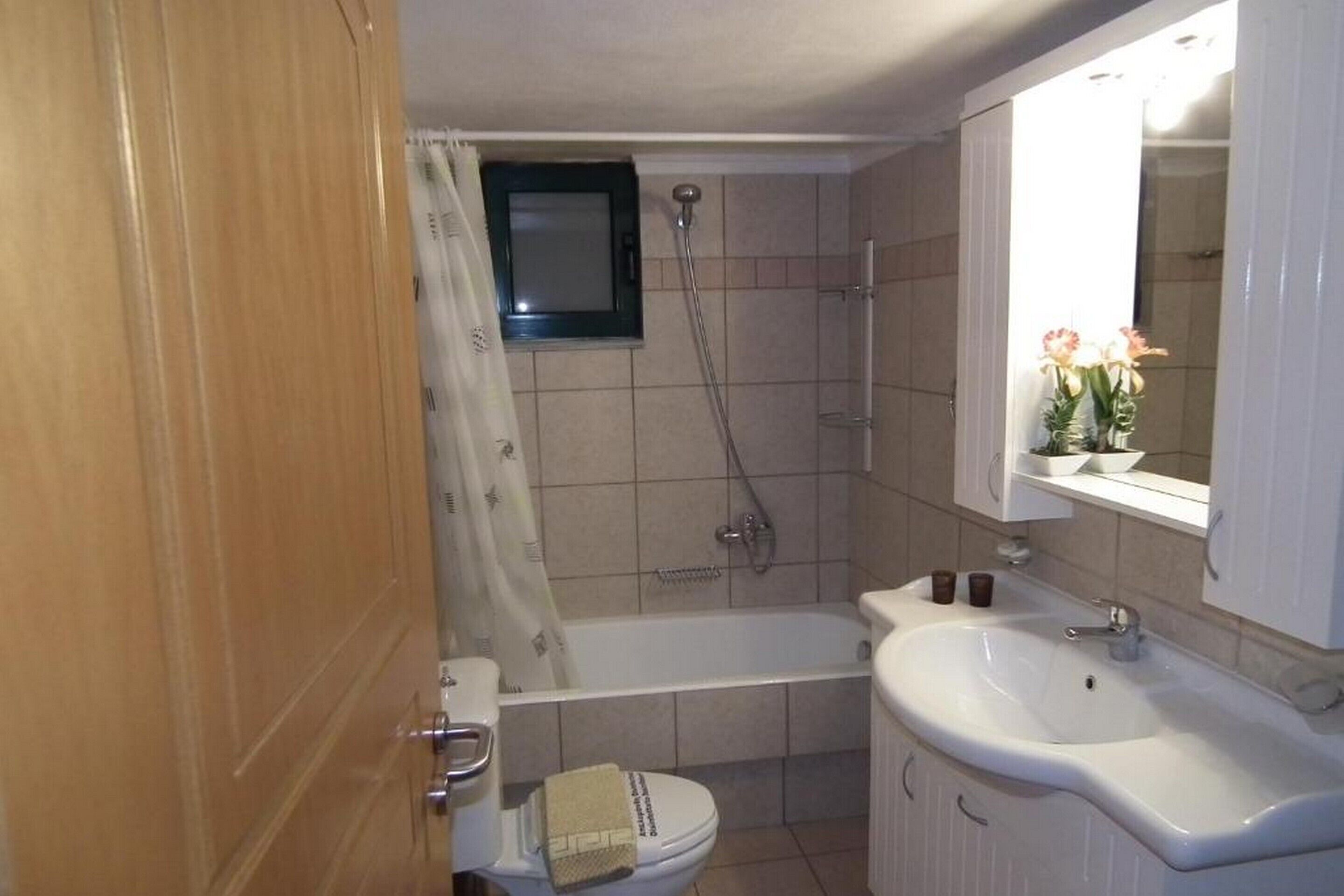 Un baño con bañera, inodoro, lavamanos y un espejo sobre el lavamanos.