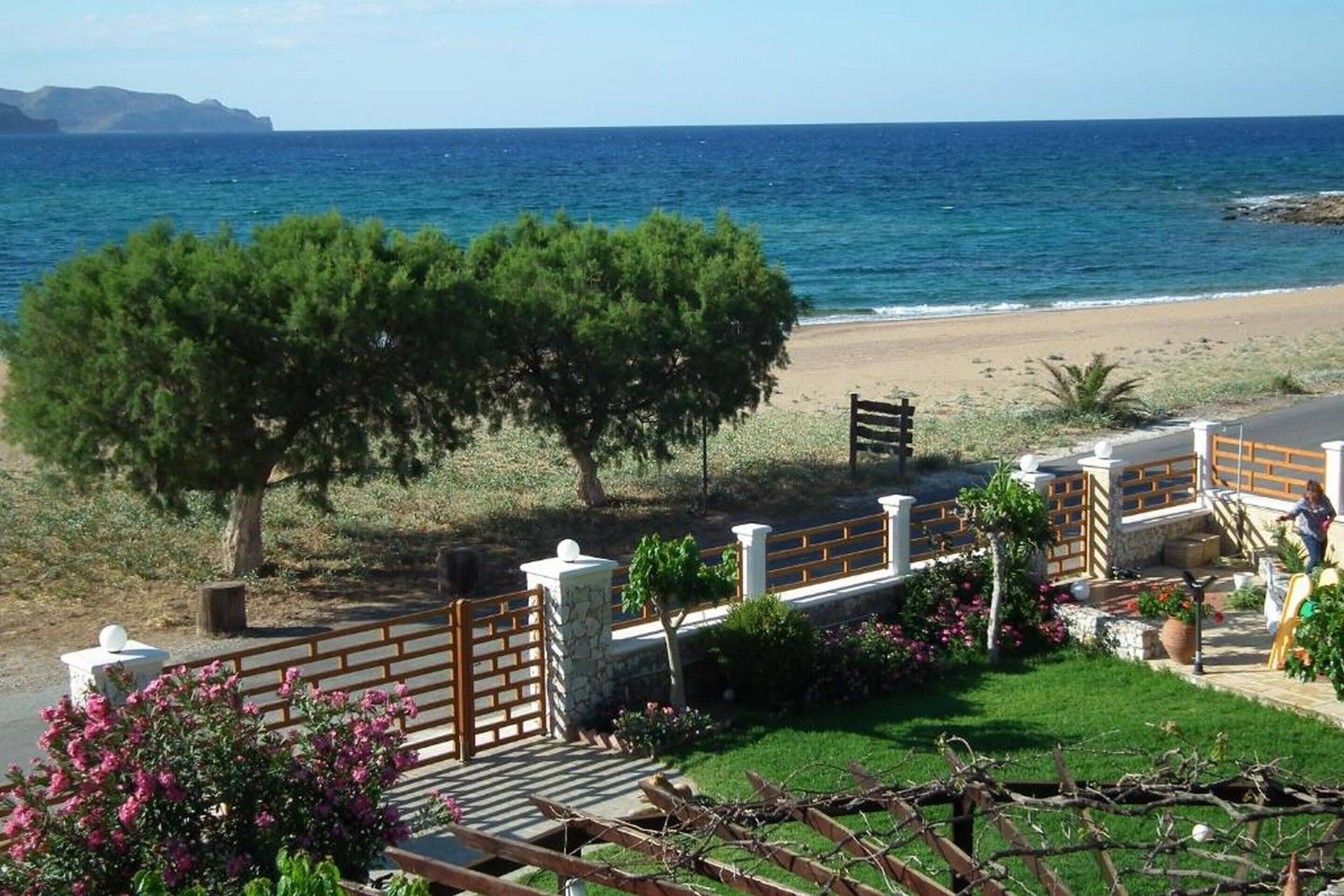 A coastal property with a paved pathway, a wooden fence, and a view of the sea.