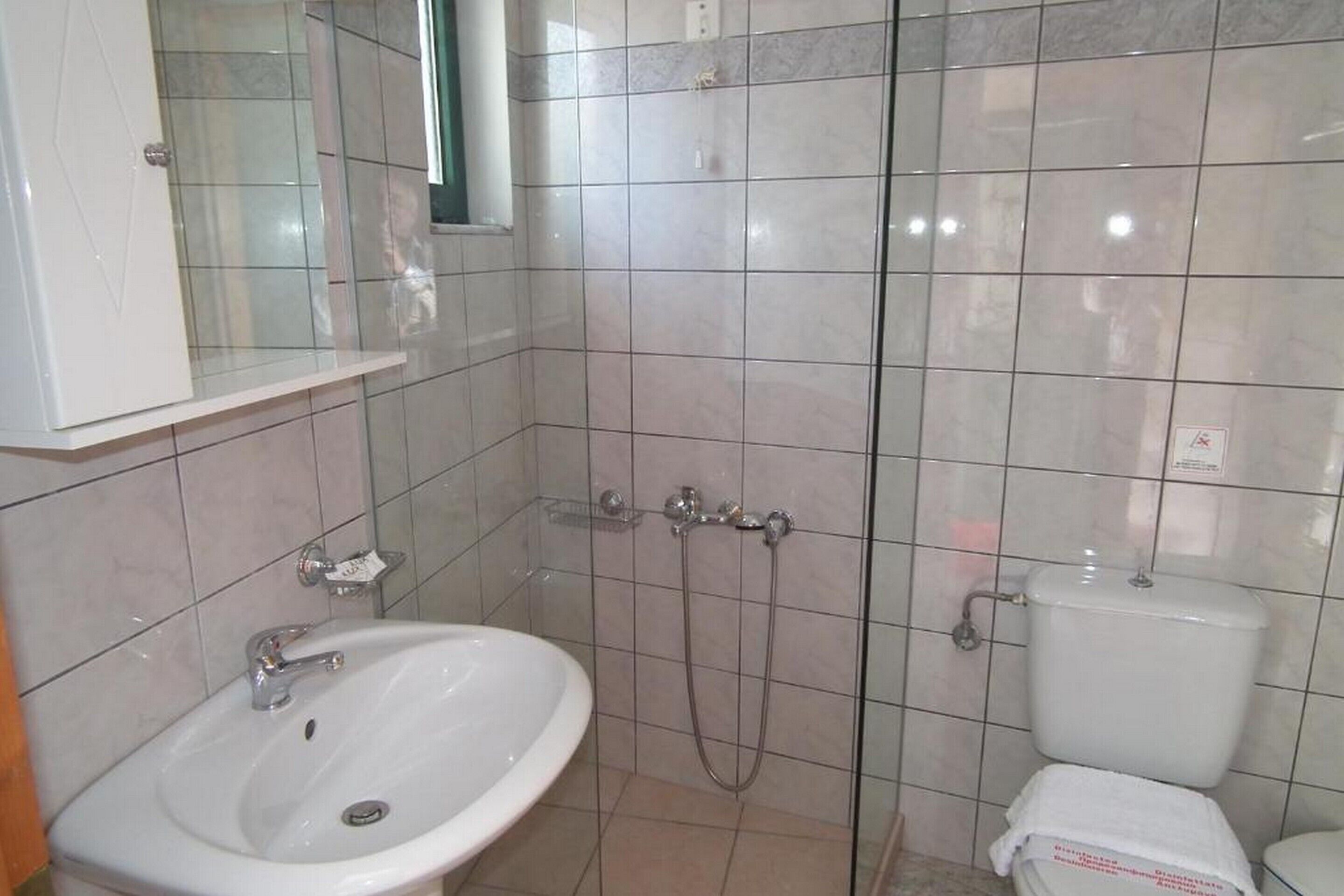 Un baño con lavamanos blanco, inodoro y cabina de ducha.