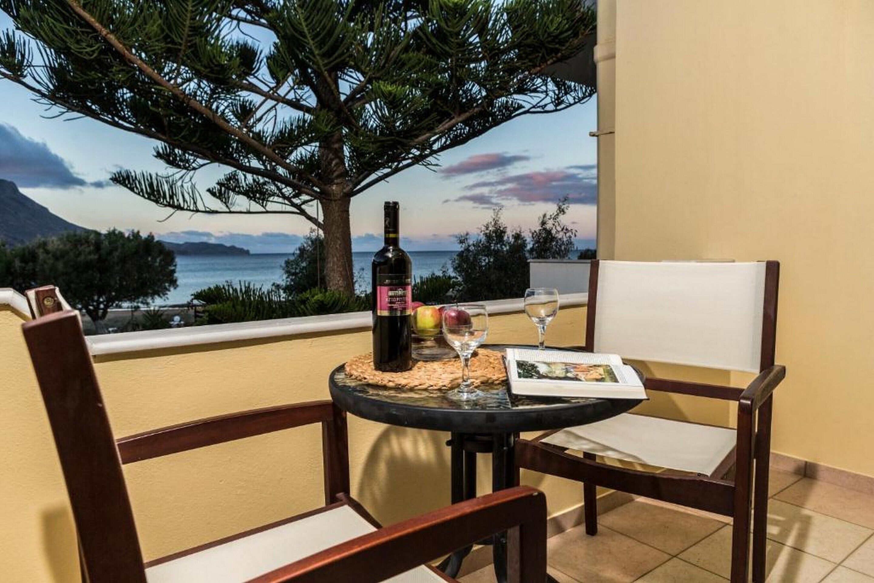 Ein Balkon mit Tisch für zwei Personen, ausgestattet mit einer Weinflasche, einem Glas und einer Speisekarte.