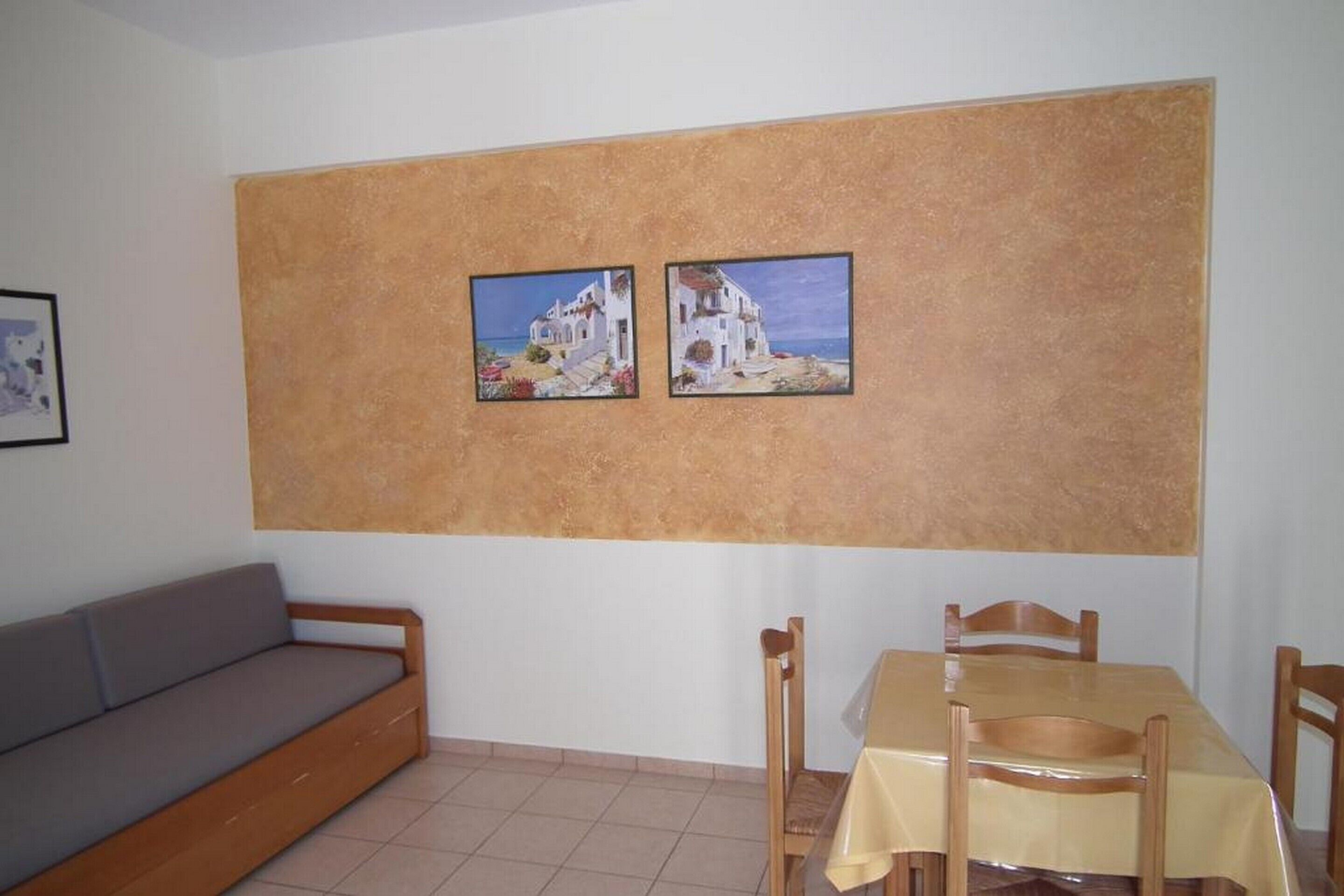 Un comedor con una mesa y sillas, un sofá y dos cuadros en la pared.