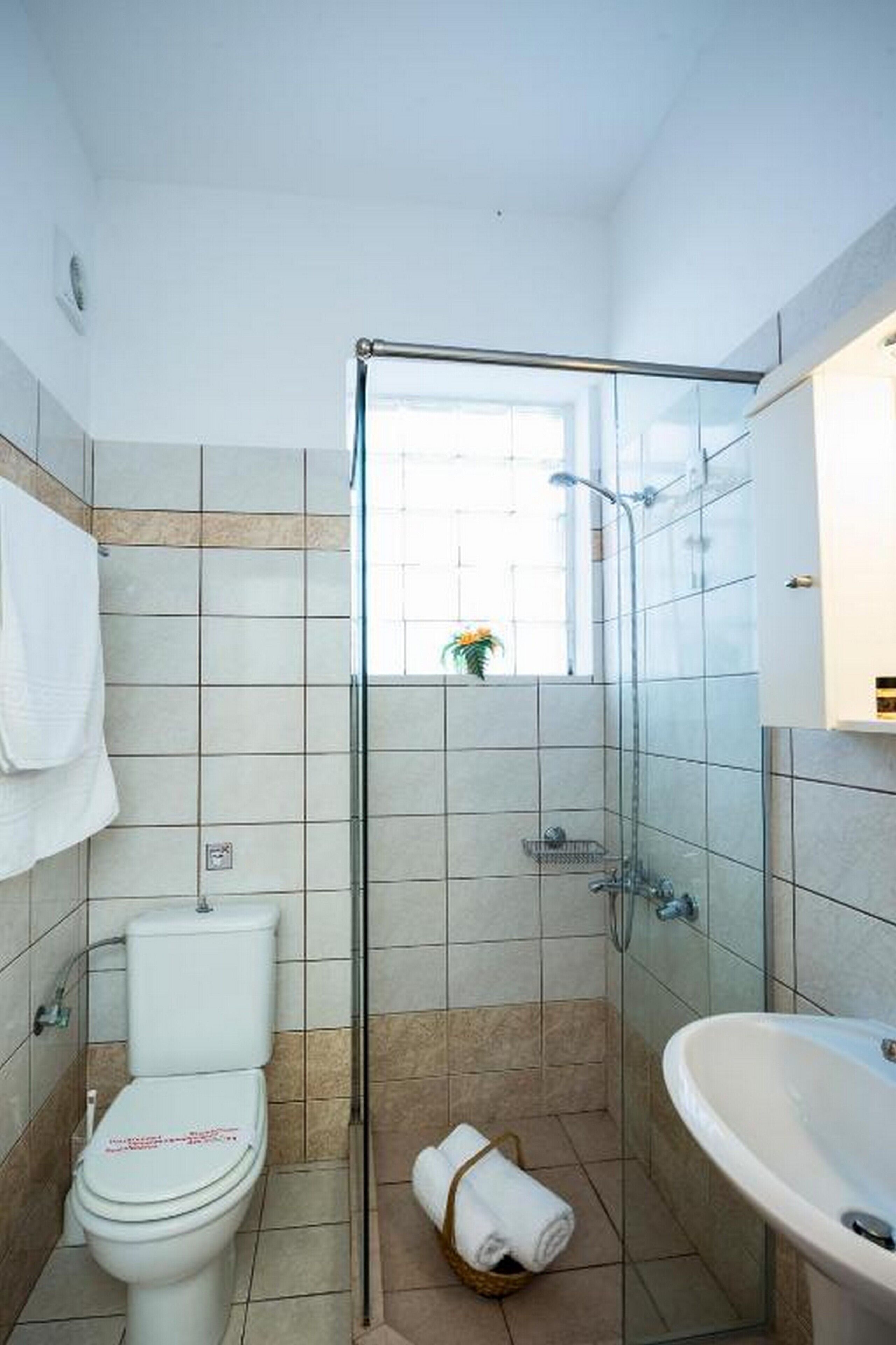 Un baño con ducha de vidrio, inodoro y lavamanos.