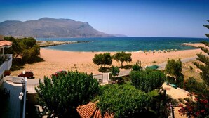 A beach with a mountain in the background, a few umbrellas, and some greenery. - Gramvoussa Bay (Kissamos)