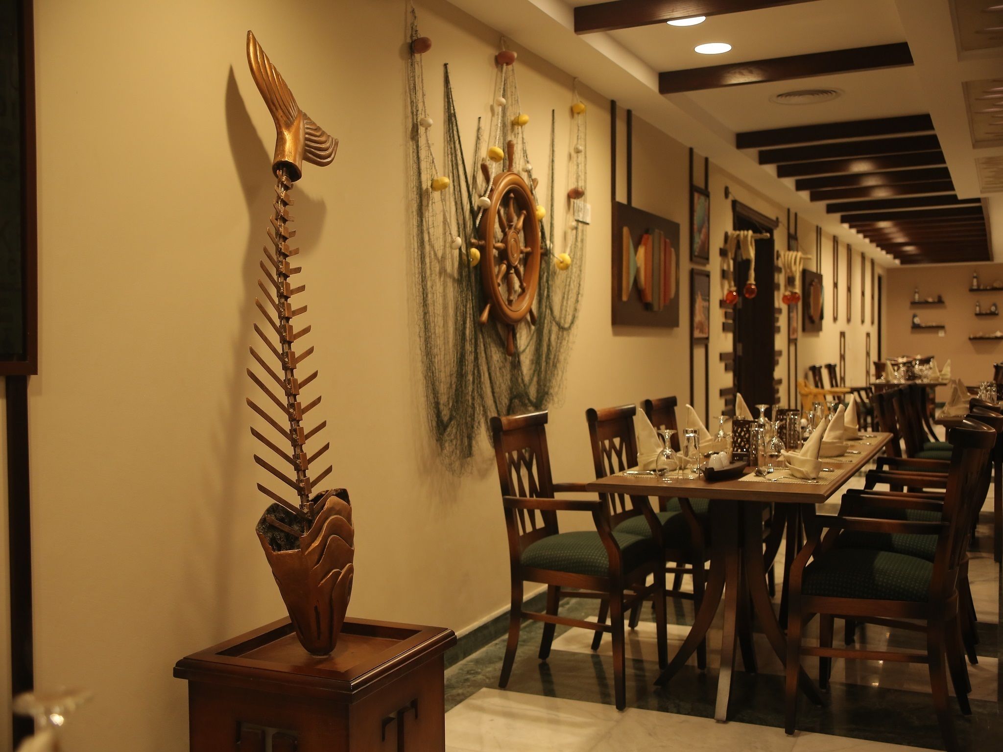 A dining area with a long table set for multiple guests, wooden chairs, and a decorative wall piece.