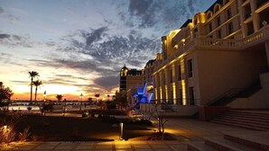 Un hotel con una fachada imponente, una entrada bien iluminada y una vista despejada del atardecer al fondo.