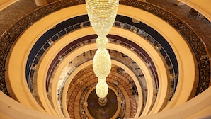 Un atrio de varios niveles con una escalera espiral central y una gran lámpara de araña ornamentada.