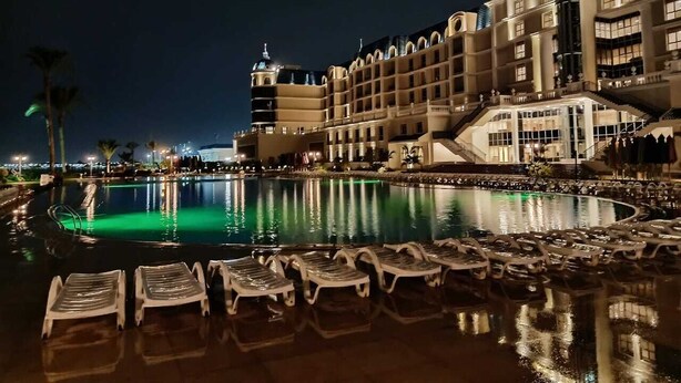 Un hotel con una piscina grande, varios pisos y un exterior bien iluminado.