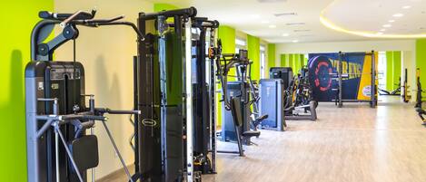Une salle de sport moderne équipée de divers appareils d’exercice, avec des murs vert vif et un logo représentant le « TOLIP El Forsan Resort ISMAILA ».
