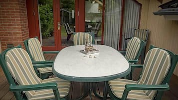 A round table with six chairs, each with striped cushions, on a wooden deck.