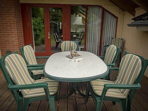 A round table with six chairs, each with striped cushions, on a wooden deck. - Juwel Feriendorf - Reihenhaus Sören (Gluecksburg)