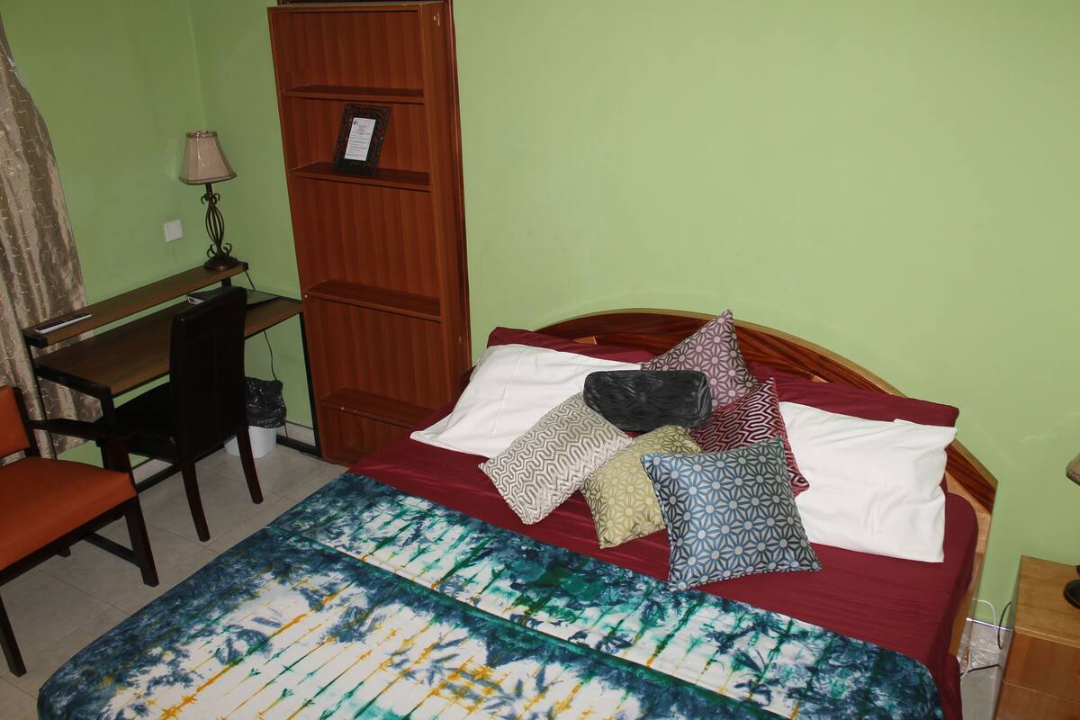 Um quarto com uma cama, uma escrivaninha e uma cadeira.