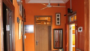 A corridor with a wooden door at the end, a ceiling fan, and a tiled floor. - Jesiwa B's Little Palace (Accra)