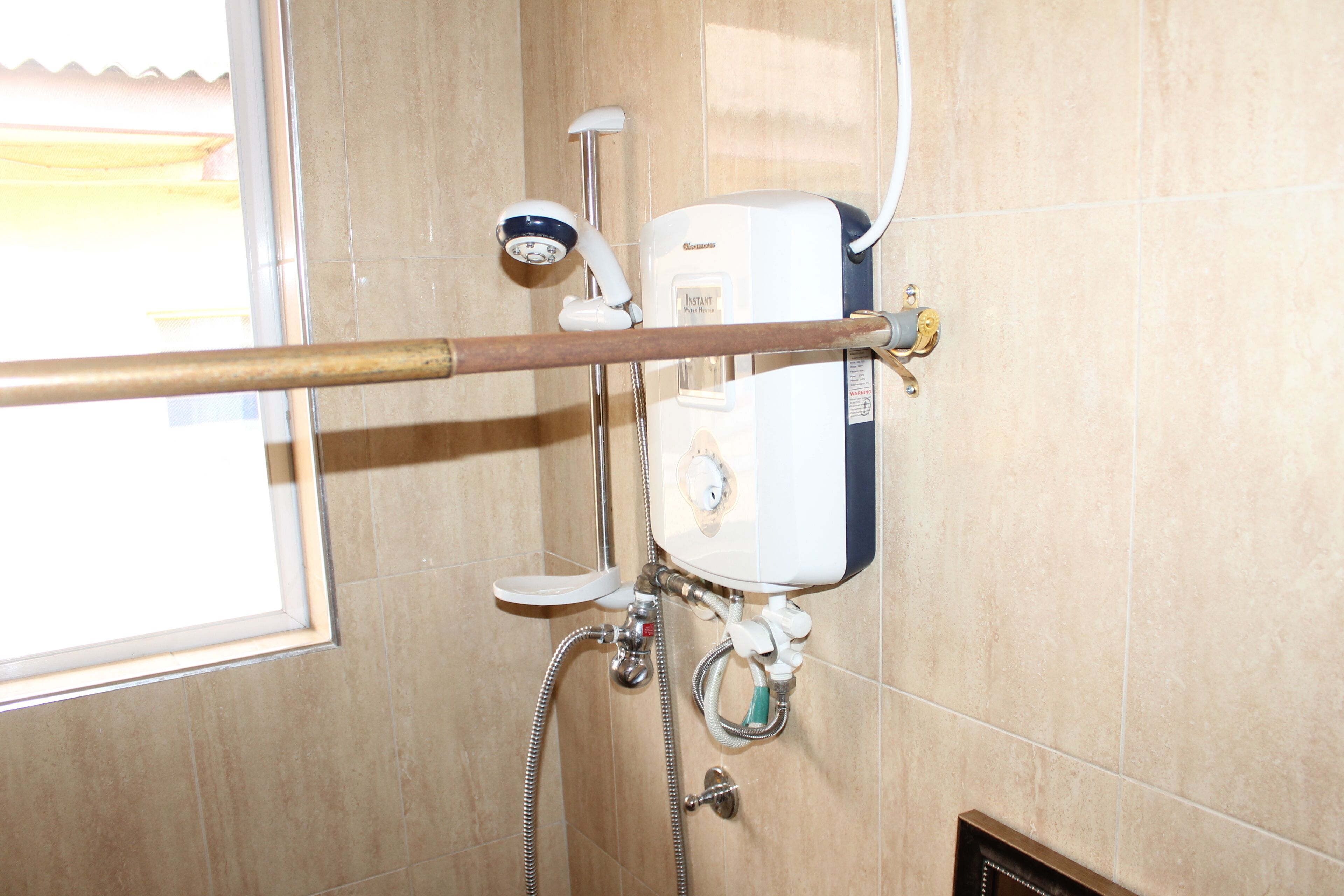 A bathroom with a shower, toilet, and a window.