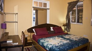 A bedroom with a bed, a desk, a telephone, and a window with curtains. - Jesiwa B's Little Palace (Accra)