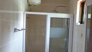 A bathroom with a glass-enclosed shower, a toilet, and a sink. - Georgetown Court (Accra)