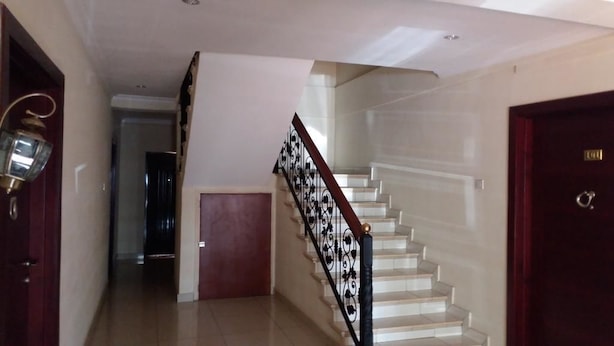 A staircase with a black railing and a wooden handrail, leading to a landing. - Georgetown Court (Accra)