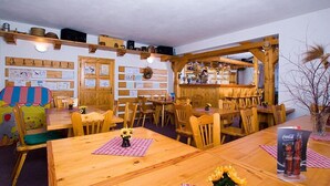 A cozy restaurant with wooden tables and chairs, a bar area, and various kitchen utensils on shelves. - Pension Samohel (Rokytnice nad Jizerou)