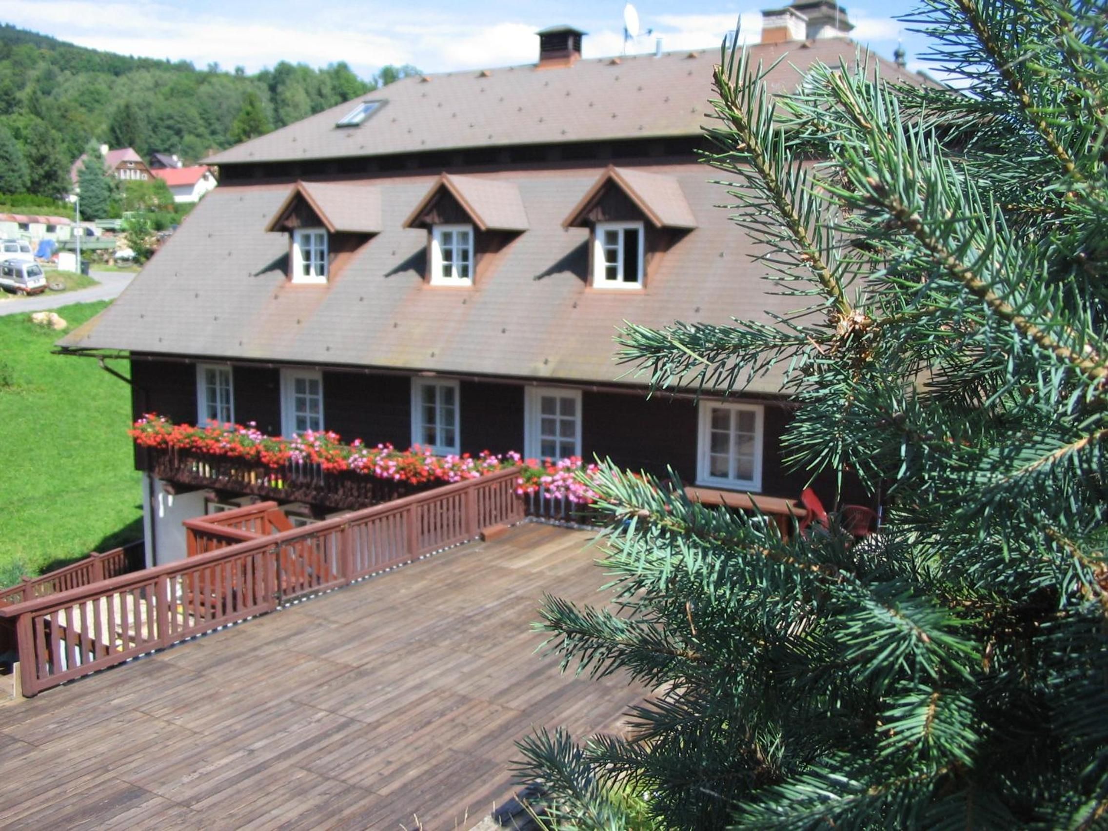 A two-story building with a wooden deck and a flower garden.