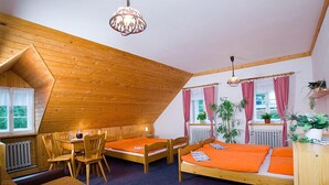 A cozy room with a sloped ceiling, wooden furniture, and a dining area. - Pension Samohel (Rokytnice nad Jizerou)