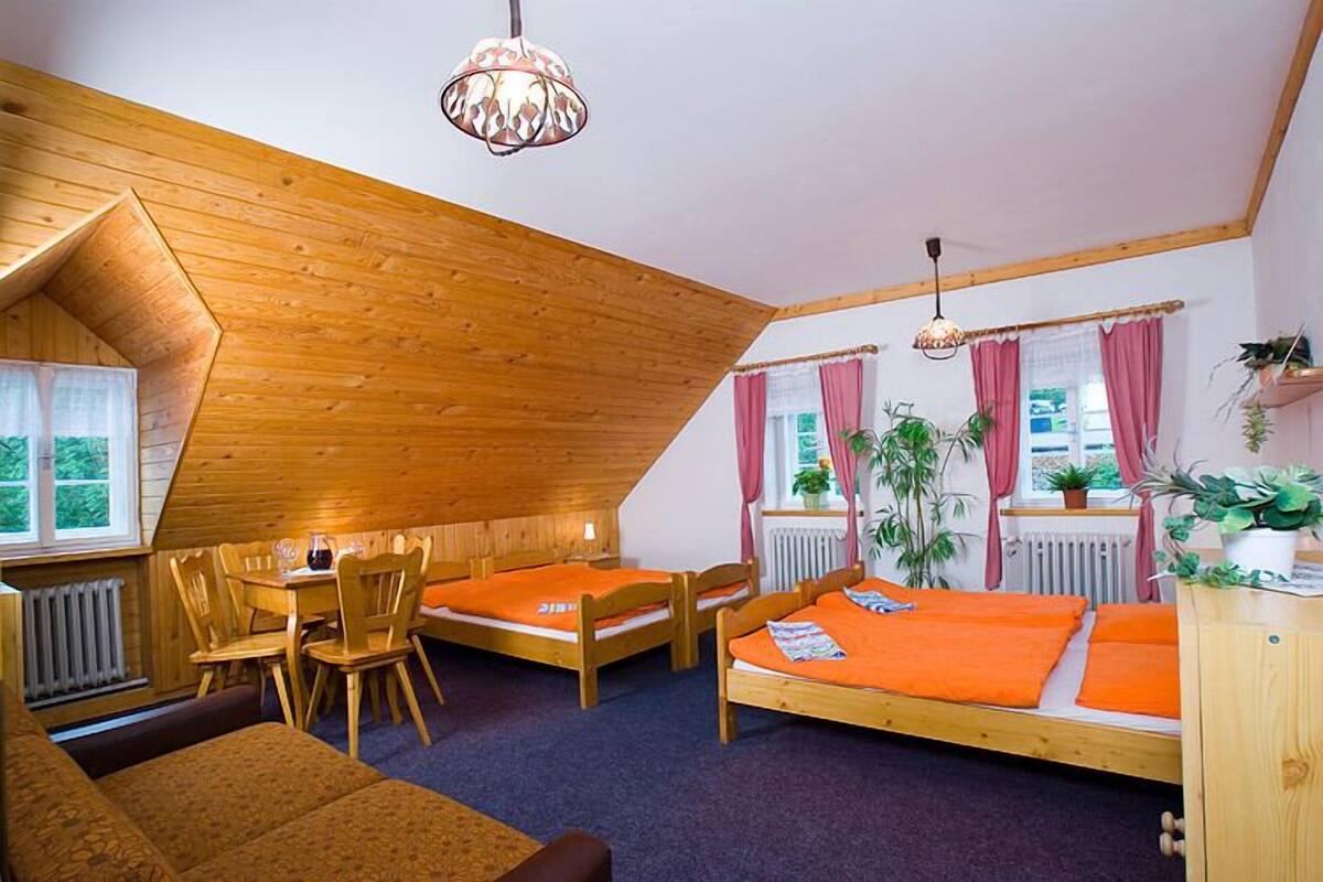 Um quarto acolhedor com teto inclinado, móveis de madeira e um espaço de refeições.
