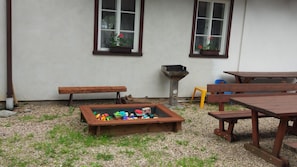 An outdoor seating area with wooden benches and tables, a fire pit, and a play area with colorful toys. - Pension Samohel (Rokytnice nad Jizerou)