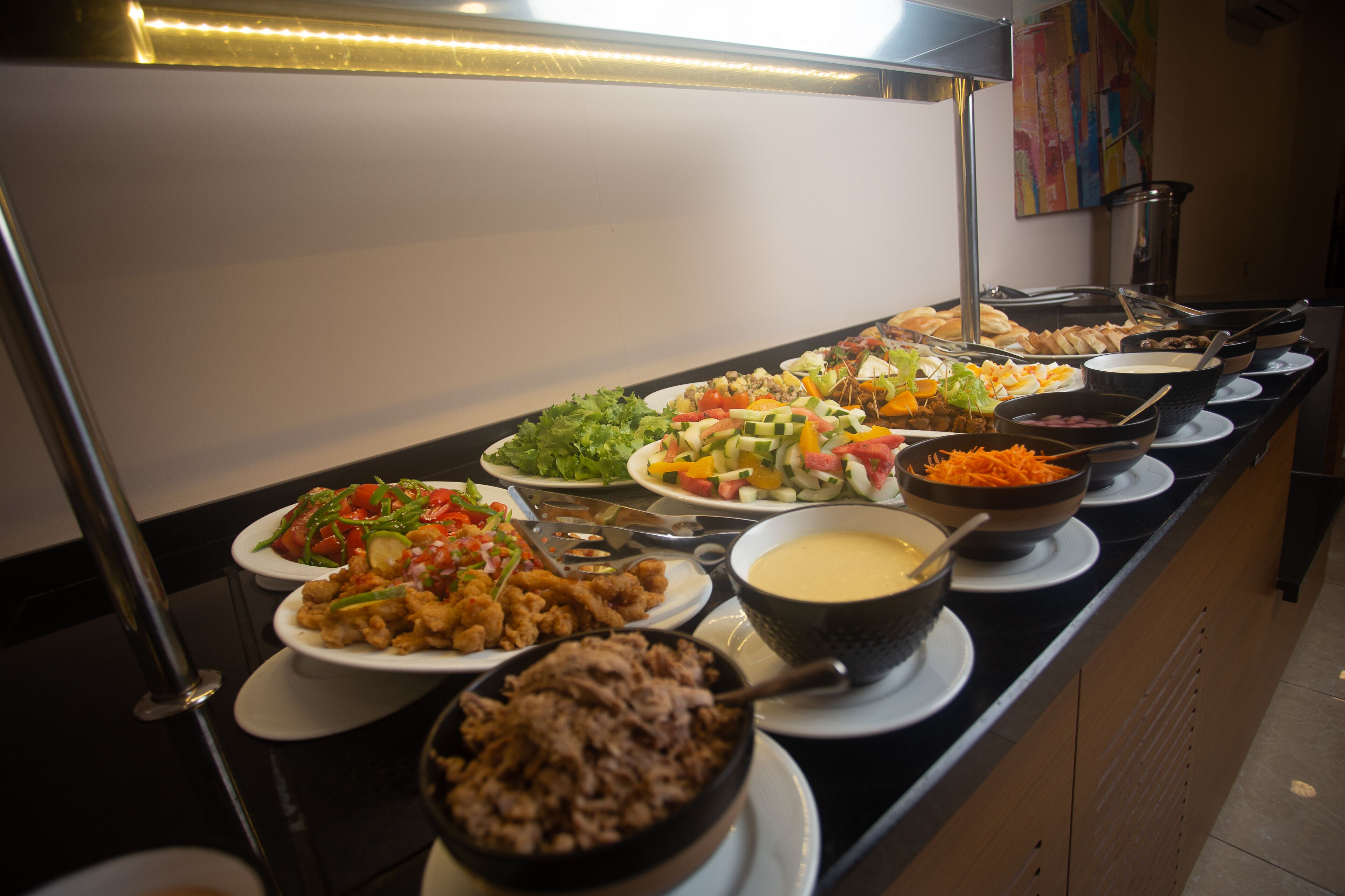 A buffet with various dishes including salads, meats, and dips.