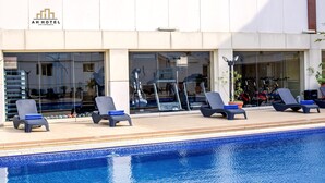 Uma área de piscina de hotel com espreguiçadeiras e equipamentos de ginástica.