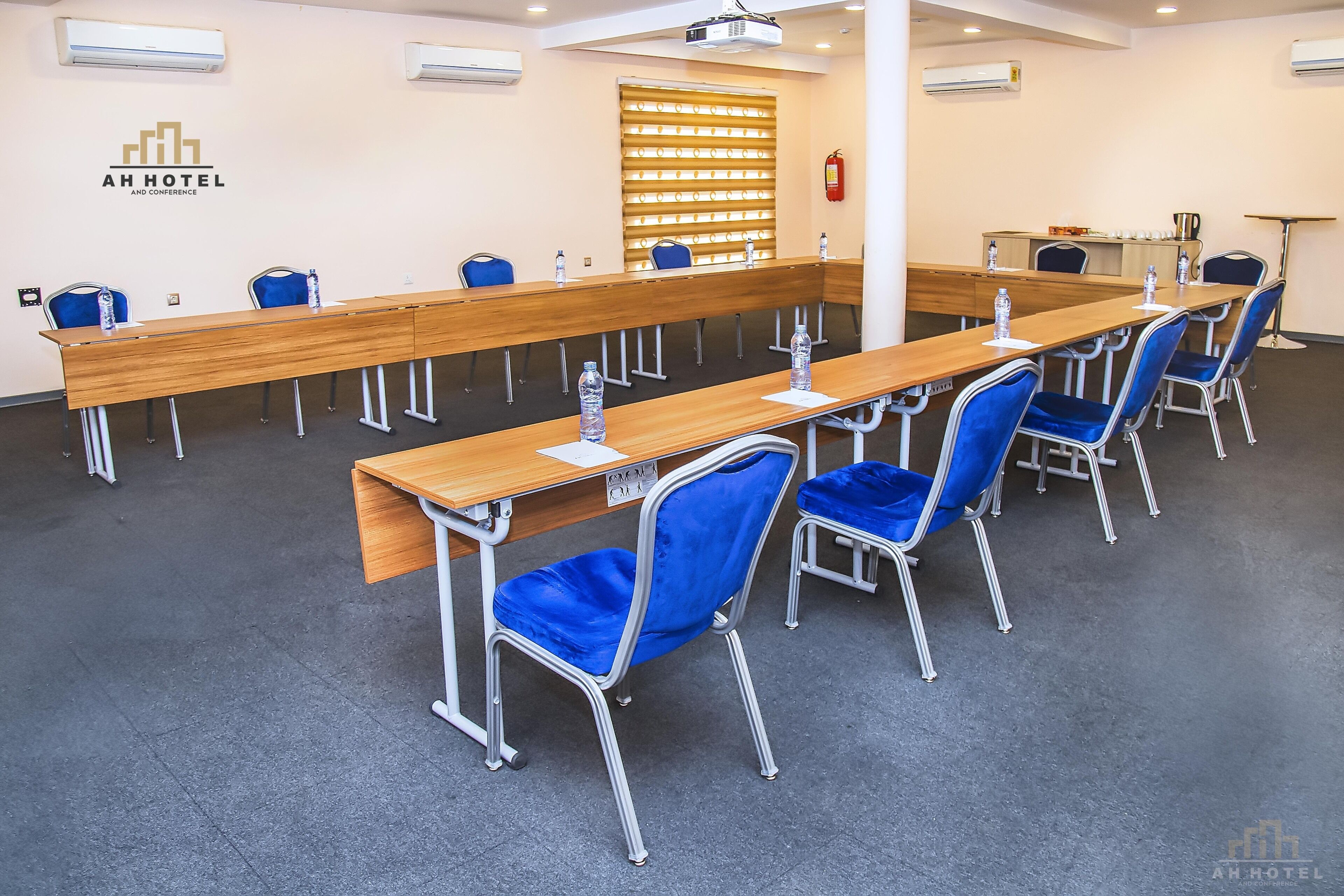 A conference room with a long wooden table, blue chairs, and water bottles.