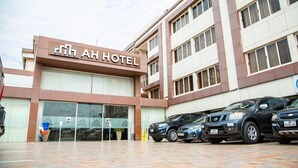 Exterior do Hotel AH com área de estacionamento à frente.