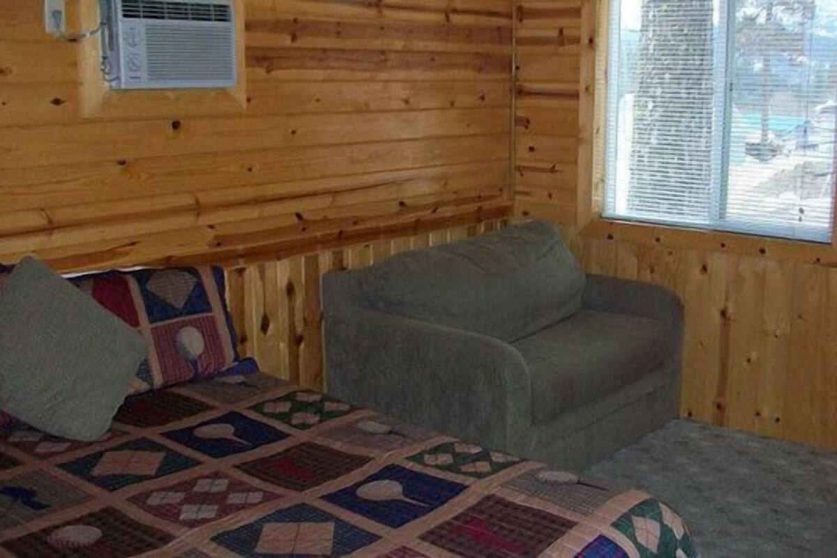 A cozy cabin room with a bed, a couch, and a window.