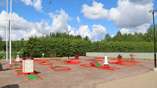 A playground with various play structures, including slides and climbing areas, set against a backdrop of trees and a clear sky. - Hotelli Wanha Kammari (Karstula)
