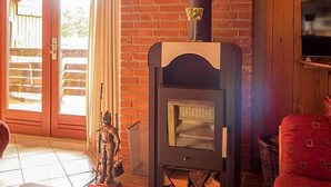 A cozy room with a brick fireplace, a television mounted on the wall, and a wooden ceiling. - Ferienwohnung Polly (Gluecksburg)