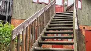 A wooden staircase leading to a building with a green facade and red accents. - Ferienwohnung Polly (Gluecksburg)