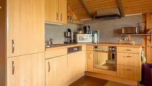 A compact kitchen with wooden cabinets, a microwave, a coffee maker, and a toaster. - Ferienwohnung Polly (Gluecksburg)