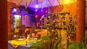 A restaurant with a brick wall, hanging decorations, and a table set for dining. - Jeane's Appart Hotel (Lomé)