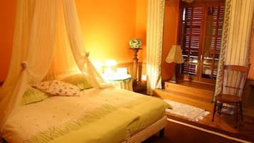 Una cama con dosel, una mesita de noche con lámpara, una silla y vistas a una puerta y ventana de madera.