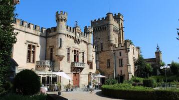 Un edificio con aspecto de castillo, con patio, muros de piedra y una torre.