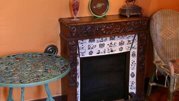A room with a fireplace, a mirror, a table, and a chair.