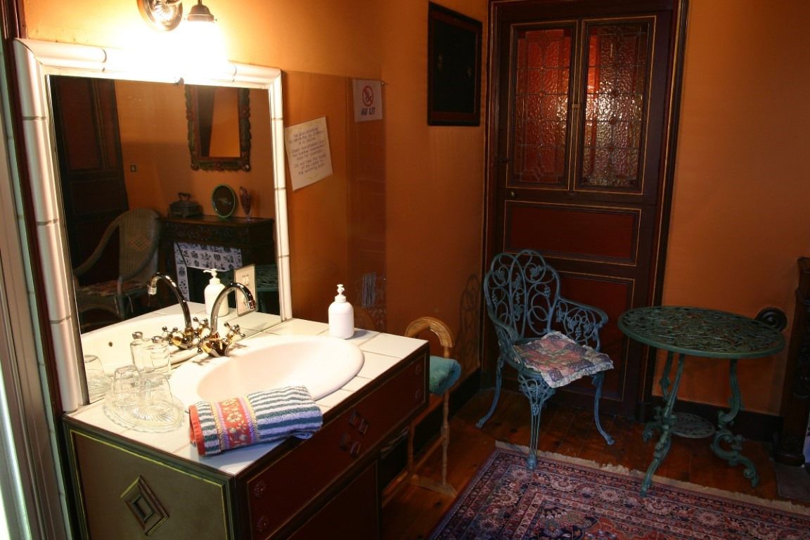Un baño con lavamanos, espejo y una silla cerca de la puerta.