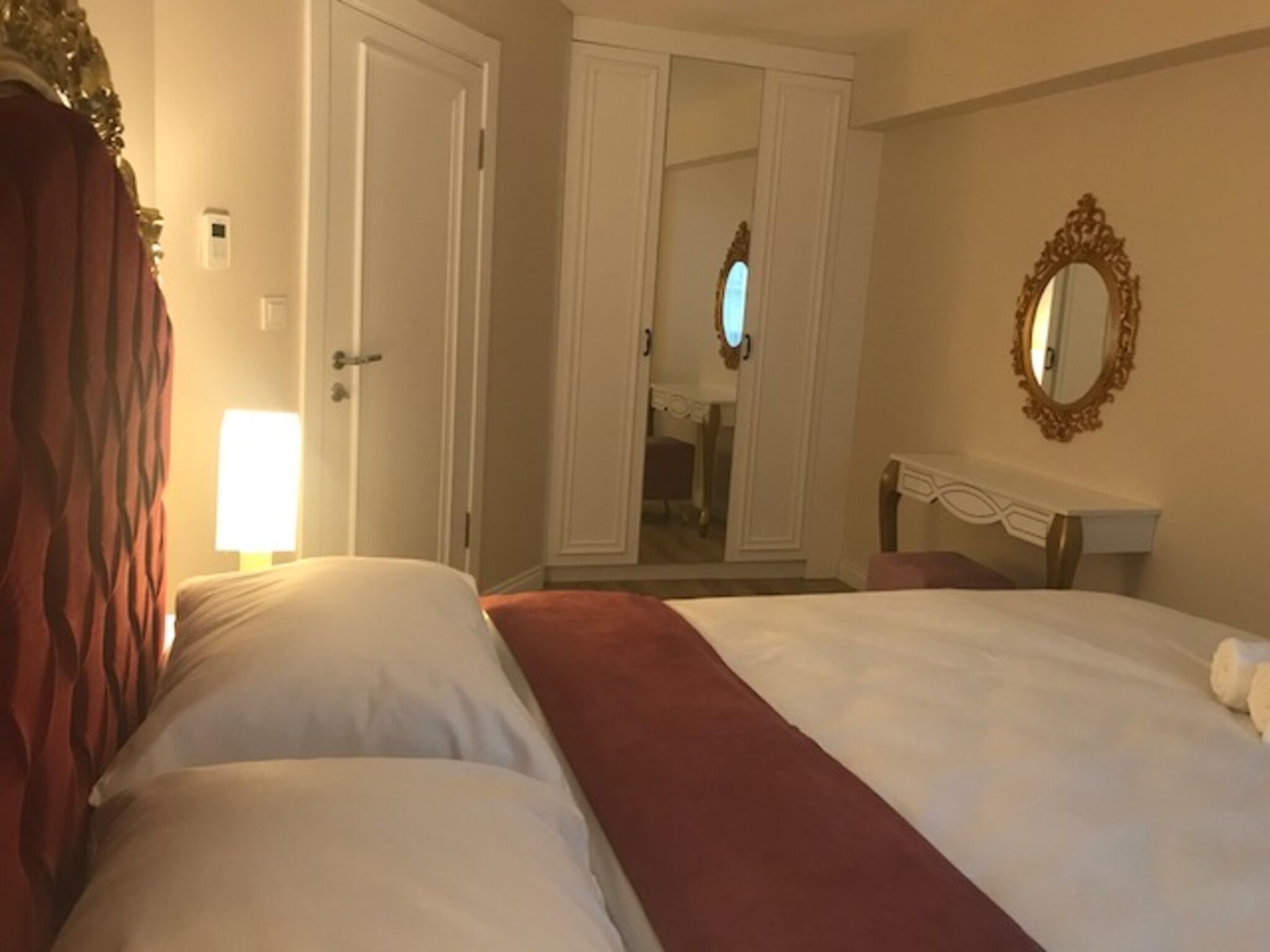 Habitación de hotel con dos camas, un espejo y una puerta que da al baño.