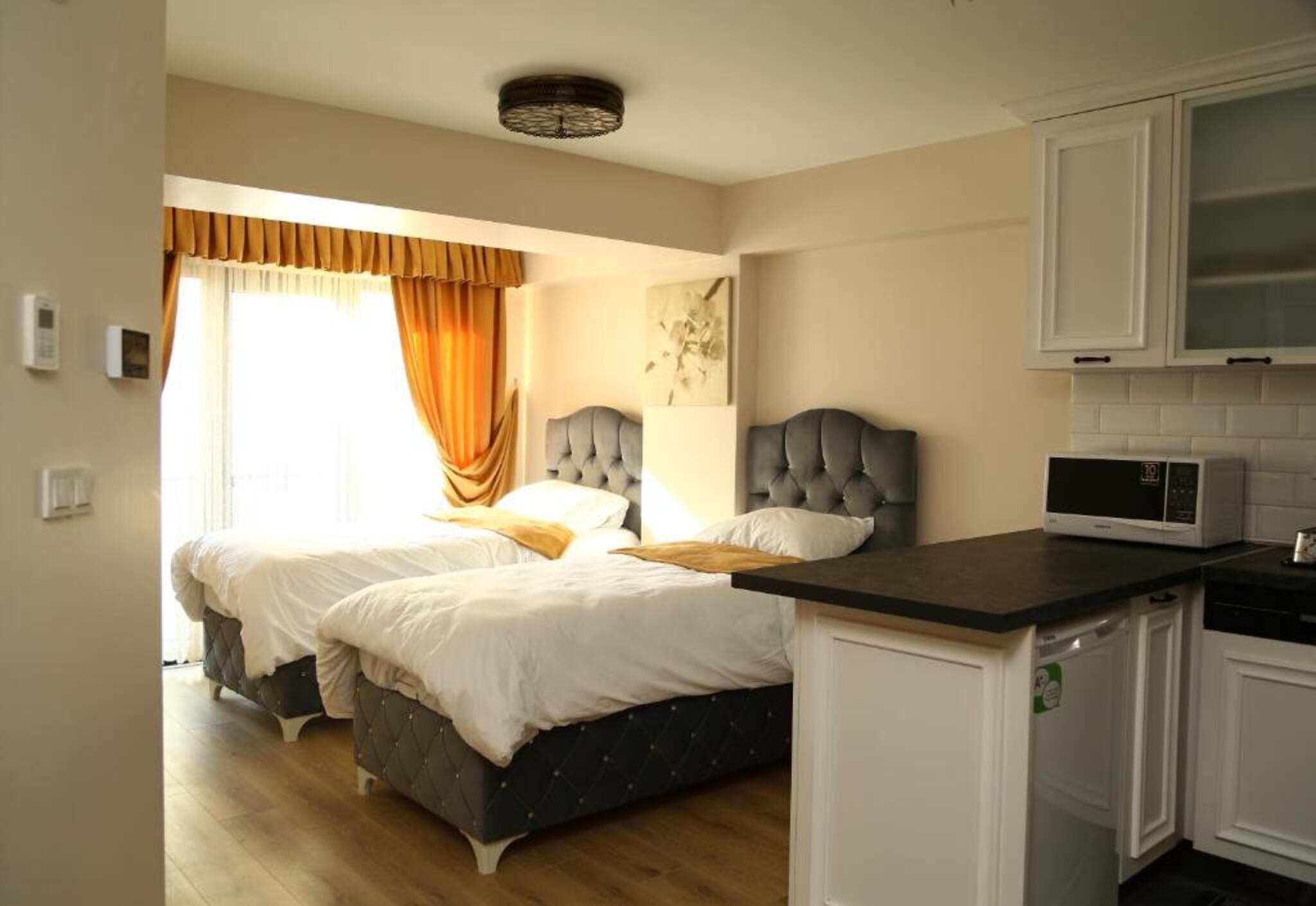 Un dormitorio con dos camas, un pequeño kitchenette y un baño.