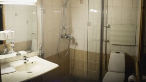 A bathroom with a shower, toilet, sink, and mirror. - Hotelli Kittilä (Kittila)
