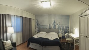 A modern hotel room with a bed, desk, chair, and a view of a snowy landscape through the window. - Hotelli Kittilä (Kittila)