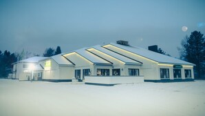 A large, modern building with a flat roof and multiple windows, surrounded by snow. - Hotelli Kittilä (Kittila)