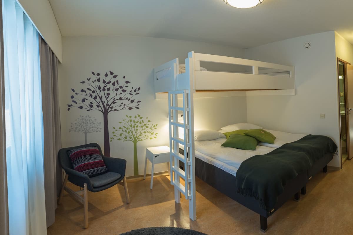 Ein Zimmer mit Etagenbetten, einem Schreibtisch, einem Stuhl und einer Wandsticker-Motivierung von einem Baum.