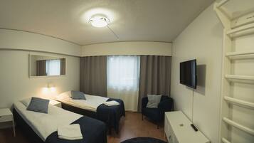 Habitación de hotel con dos camas, un escritorio, una silla, un televisor y una ventana con cortinas.