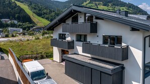 Ein modernes, zweistöckiges Haus mit Balkon, Auffahrt und Bergblick.