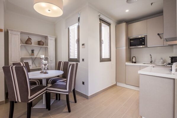Una cocina moderna con microondas, estufa y lavamanos. Hay un comedor con mesa y sillas.