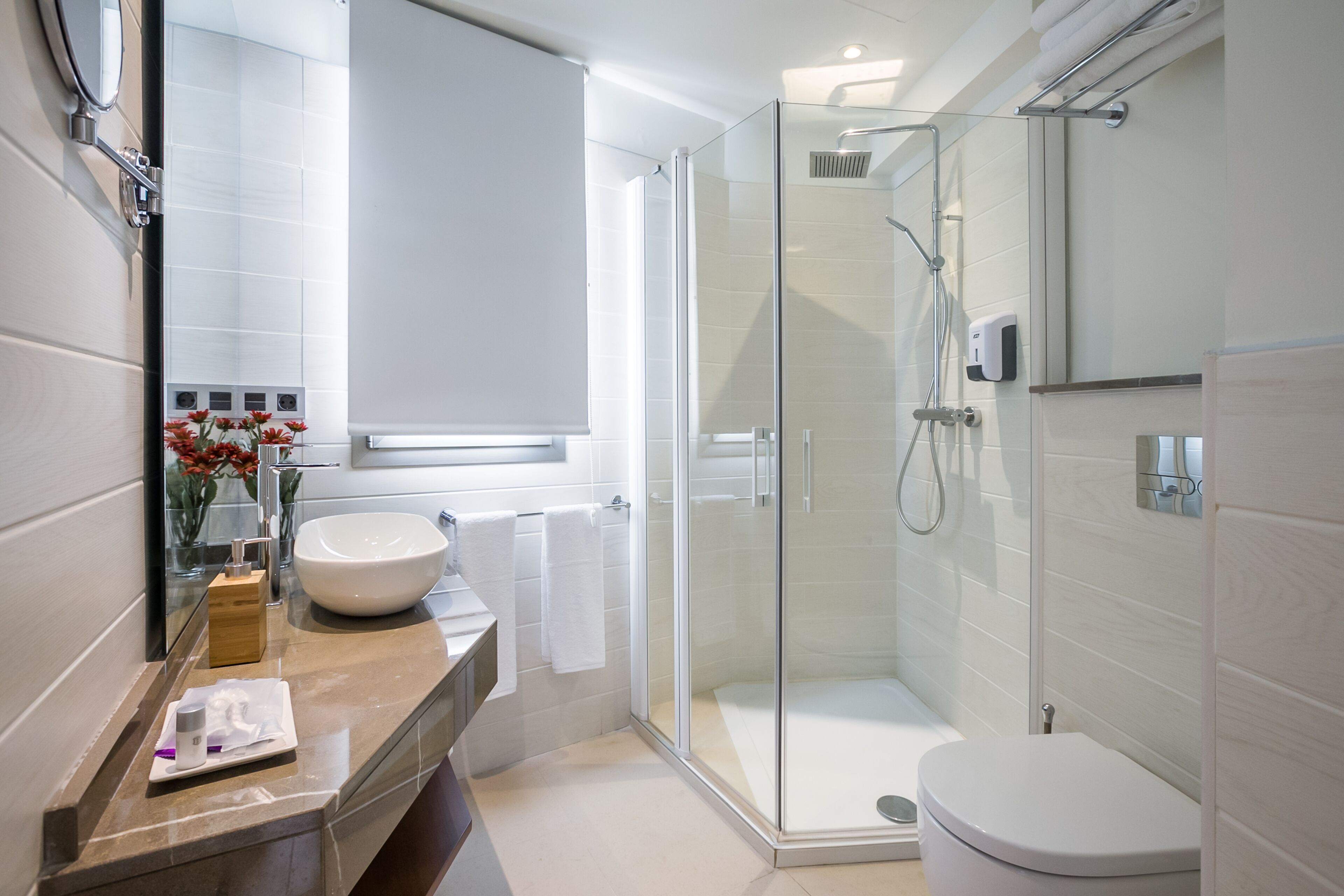 A modern bathroom with a glass-enclosed shower, a white sink, and a mirror.