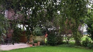 A garden with a brick wall, potted plants, and a grassy lawn.